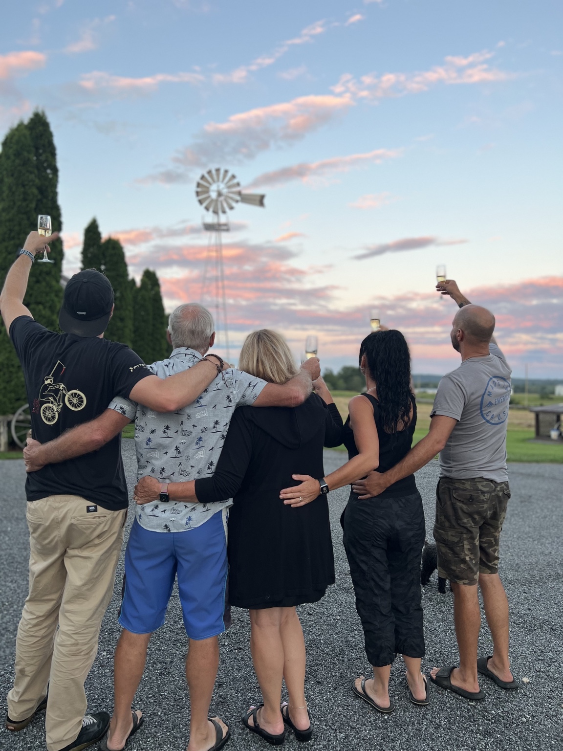 Un groupe réuni de dos devant le moulin au coucher du soleil.